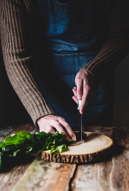 Ręce siekające zioła nad deską